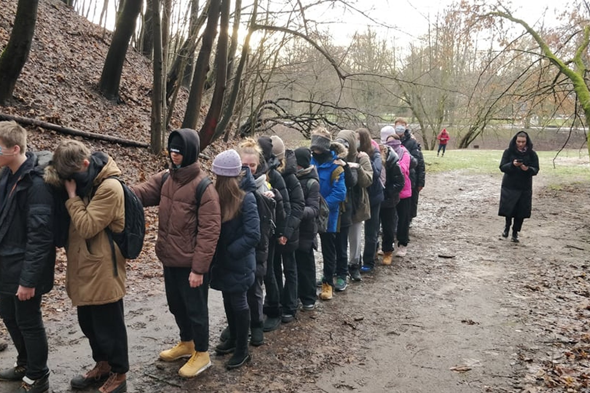 Nuotraukoje daug vaikų susotjusių eilute ant tako, kuris veda į Didžiąją griovą. Kiekvienas laiko bent vieną ranką kitam už peties ir visi yra užsidengę savo akis kepurėmis arba kaukėmis. Vienas vyras eilutės pradžioje su kuprine stebi ką jie daro. Eilutė