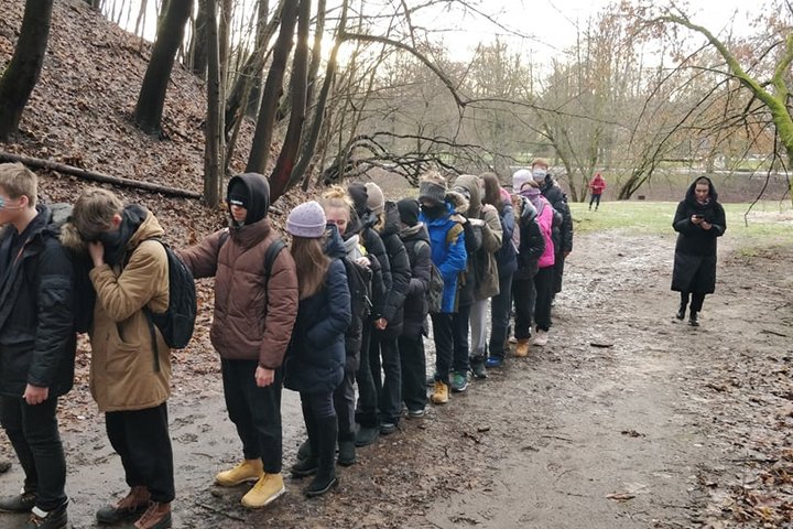 Nuotraukoje daug vaikų susotjusių eilute ant tako, kuris veda į Didžiąją griovą. Kiekvienas laiko bent vieną ranką kitam už peties ir visi yra užsidengę savo akis kepurėmis arba kaukėmis. Vienas vyras eilutės pradžioje su kuprine stebi ką jie daro. Eilutė