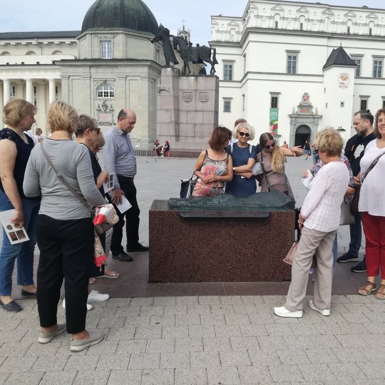 Grupė žmonių apžiūrinėja bronzinį maketą, kuris yra Katedros aikštėje. Yra šita diena, nors ir ruduo.