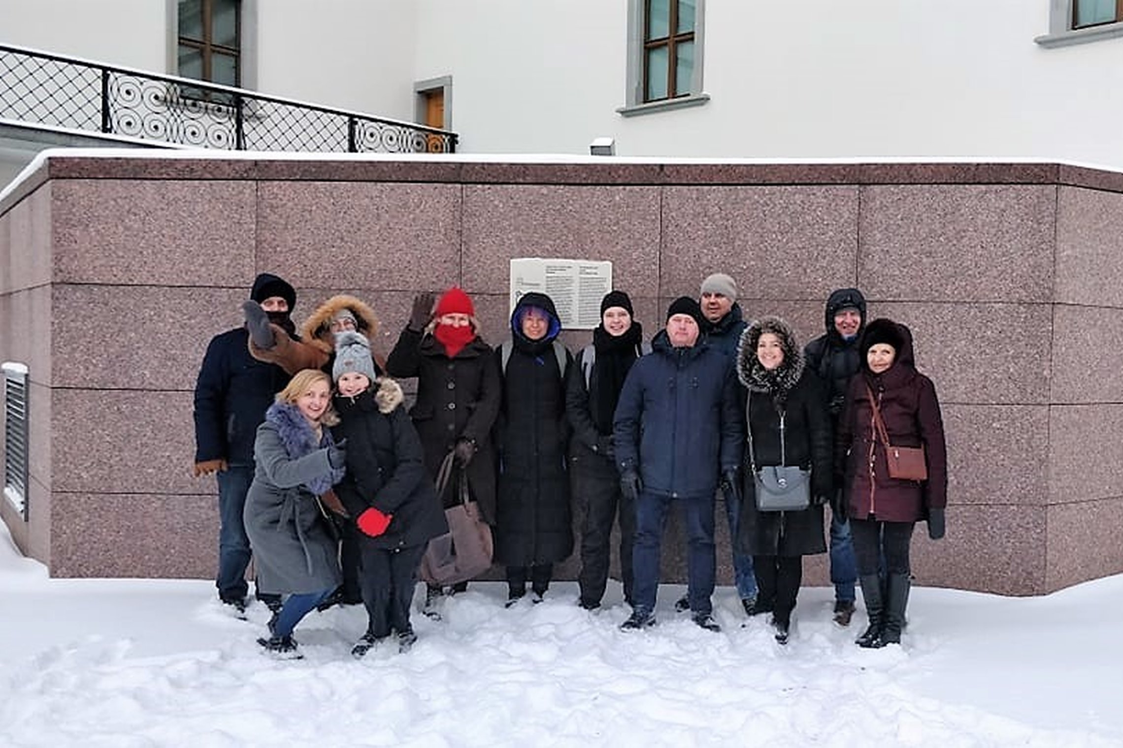 Ekskursijos dalyviai sustoję Valdovų rūmų kieme prie vietos, kur kažkada stūksojo Gedimino aikų gynybinis bokštas. Ekskursija vyksta žiemos metu - aplinkui daug sniego. Ekksursijos dalyviai pozuoja nuotraukai, šypsosi.