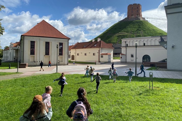 Vaikai bėga link Gedimino bokšto, Žemutinės pilies teritorijoje, giedrą vasaros dieną