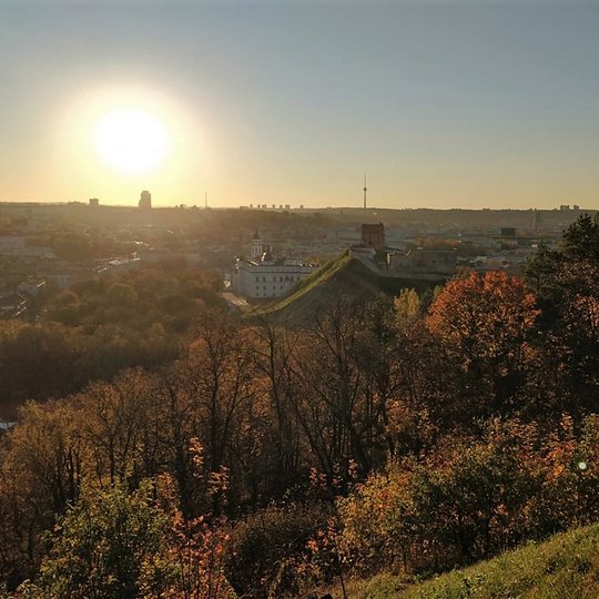 Nuostabi ir šilta rudens diena ir nuotraukoje daug vaiskaus dangaus. Saulė dar aukštai, bet jau ritasi už horizonto žemyn. Nei vieno debesėlio. Vaizdas nuo Trijų kryžių kalno. Matosi Gedimino pilis, Valdovų rūmai ir visas miestas. Nuotraukos pirmame plane