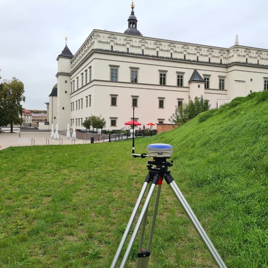 Ant Valdovų rūmų stogo pastatyta geodezinio GNSS imtuvo bazinė stotis. Virš stogo matosi tolumoje Gedimino pilies bokštas.
