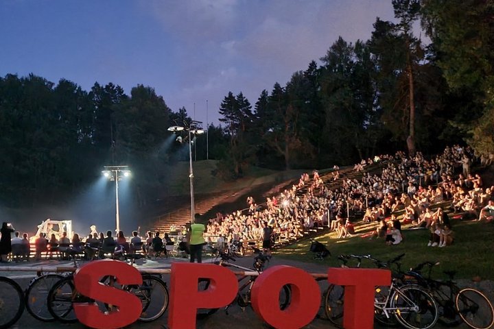  Du vyrai ir viena mašina. Geležies ir kūno kontrastas, roboto inteletas ir emocijos. Nuotraukoje yra vaizduojami žmonės, susirinkę į pasirodymą ant kalno. Nuotraukos apačioje matomi dviračiai atremti į dideles raudonas raides iš kurių susideda žodis spot