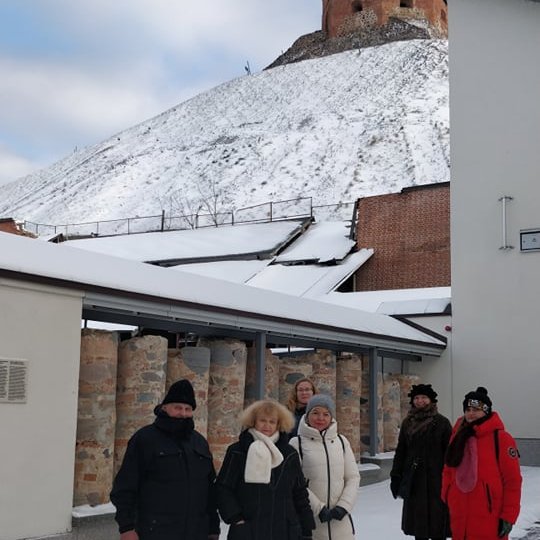 Valdovų rūmų kiemas, Gedimino kalno papėdė. Ekskursijos dalyviai pozuoja prie mūrinių kernų - iš senovinių pamatų, rūsių išpjautų mūro stulpų. Matosi apsnigtas Gedimino kalnas.