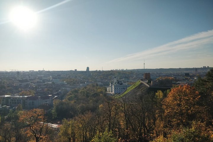 Nuostabi ir šilta rudens diena ir nuotraukoje daug vaiskaus dangaus. Nei vieno debesėlio. Vaizdas nuo Trijų kryžių kalno. Matosi Gedimino pilis, Valdovų rūmai ir visas miestas. Nuotraukos pirmame plane - daug medžių. Jie dar kažkiek, bet nedaug turi page
