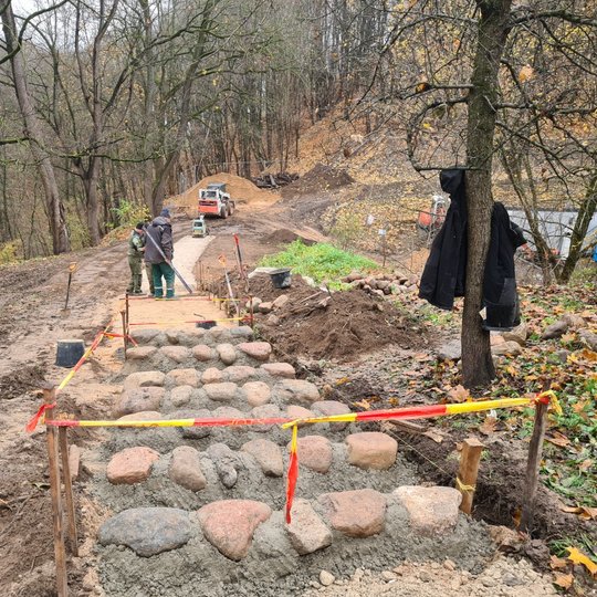 Centre arčiausiai žiūrovo esančiame nuotraukos plane yra tvarkomų laiptų konstrukcija: prikrėsta cementinės košės ir eilutėje sudėti 5 didoki akmenys. Tada lyg ir įduba ir vėl eilutė akmenų ir cemento košės. Taip suformuotos 7 laiptų pakopos, kaip minėta,