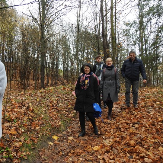 Šiltas ir gražus gana vėlyvas ruduo. Beveik visi lapai nukritę nuo medžių. Miško takeliu eina grupė žmonių. Jie atsisegioję savo paltus ir striukes. Visi geros nuotaikos, šypsosi.