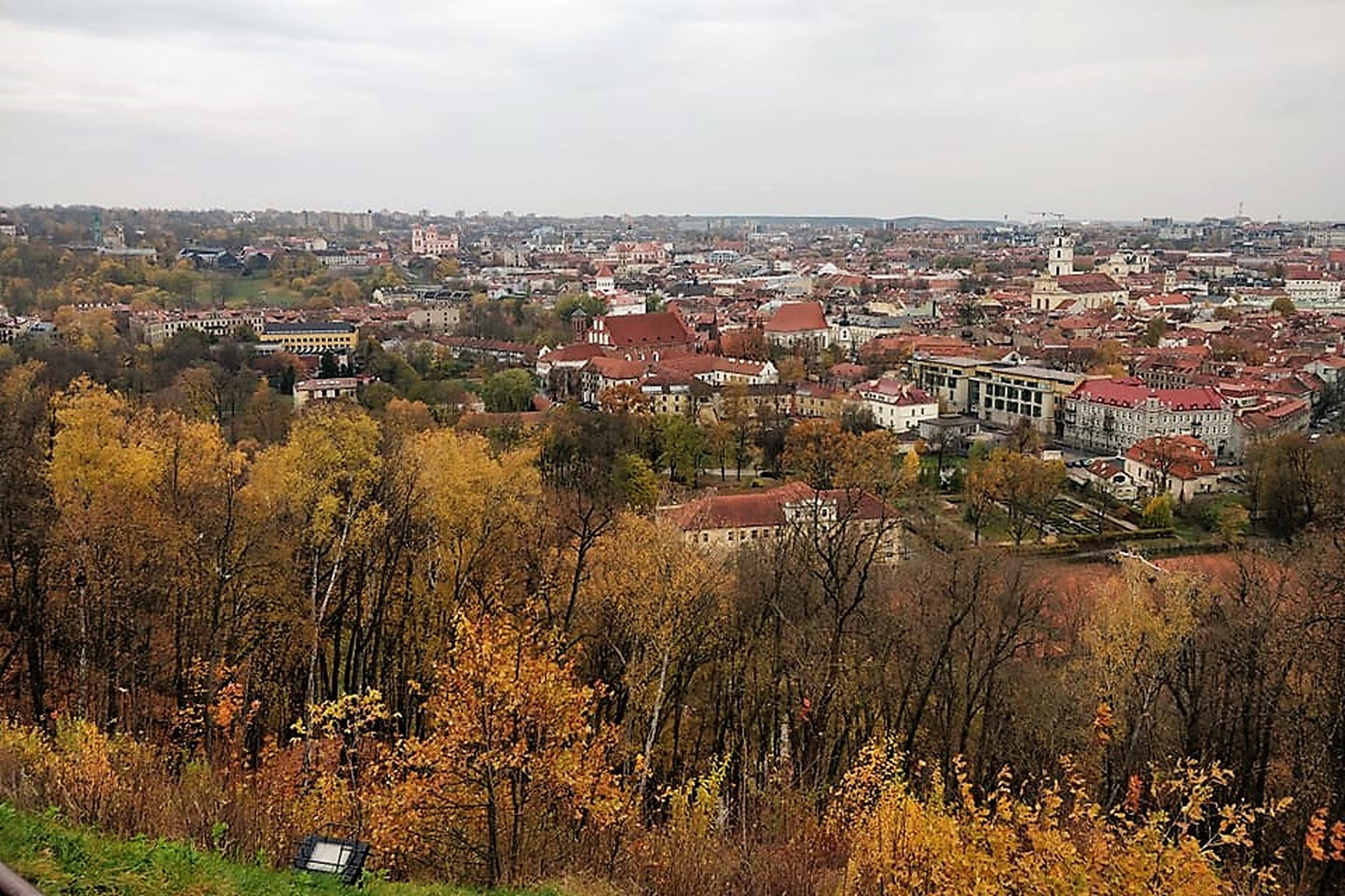 Nuostabi rudens diena ir nuotraukoje daug dangaus. Vaizdas nuo Trijų kryžių kalno. Matosi visas miestas. Nuotraukos pirmame plane - daug medžių, kurie nusispalvinę rudens spalvomis.