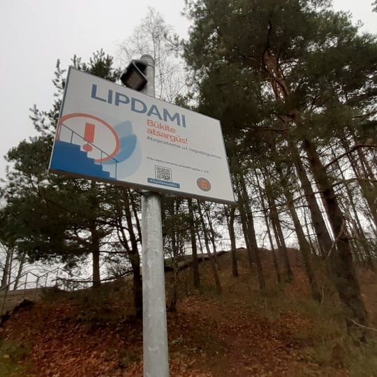 Iškelta ant ilgo koto lentelė - LIPDAMI BŪKITE ATSARGŪS. Tai perspėjimas žmonėms, nes Trijų Kryžių kalno laiptai laukia tvarkymo darbų.