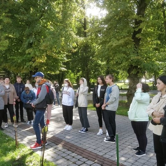 Nemaža grupė paauglių, mokinių stovi Gedimino pilies kalno papėdėje ir šaudo iš lankų į taikinius.