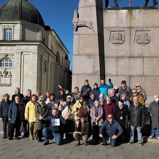 Didžiulė ekskursijos grupė pozuoja prie Gedimino paminklo Katedros aikštėje. Kairėje matosi Vilniaus katedros Šv. Kazimiero koplyčia.