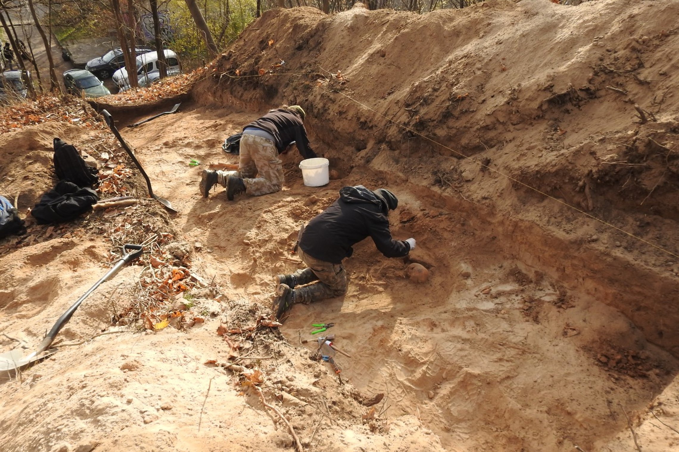 Žvalgomieji archeologiniai tyrimai Altanos kalne - perkasoje du archeologai, kurie valo nuo atkastų žmonių palaikų smėlį.