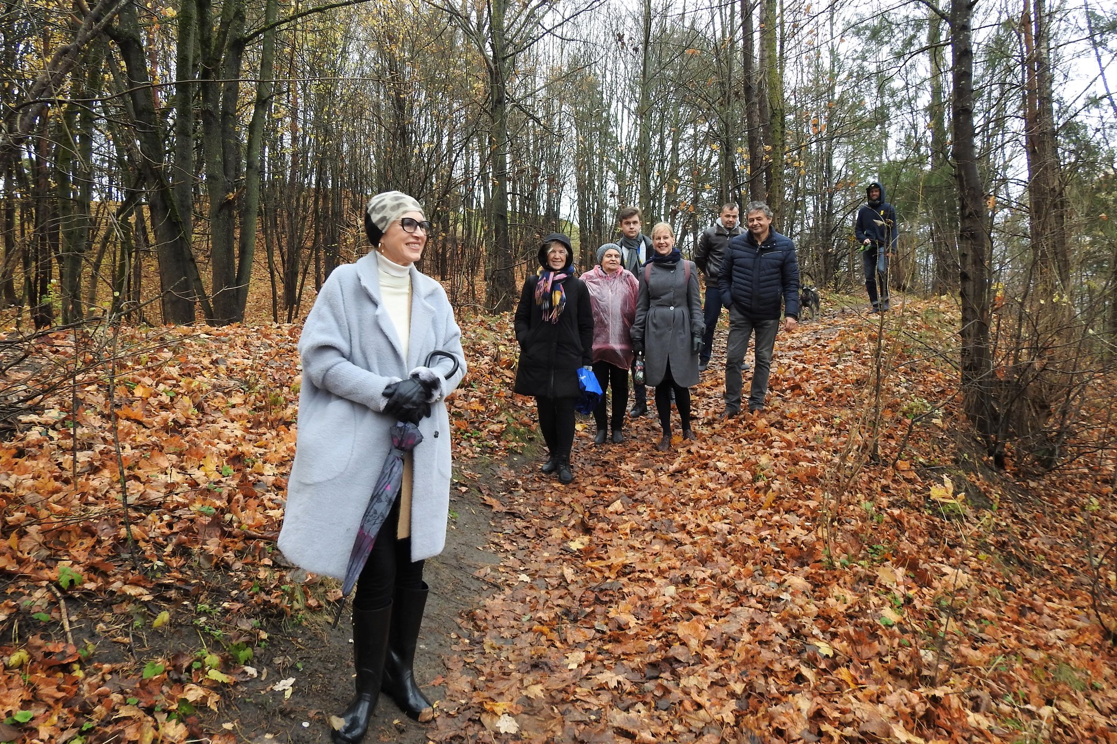 Šiltas ir gražus gana vėlyvas ruduo. Beveik visi lapai nukritę nuo medžių. Miško takeliu eina grupė žmonių. Jie atsisegioję savo paltus ir striukes. Visi geros nuotaikos, šypsosi.