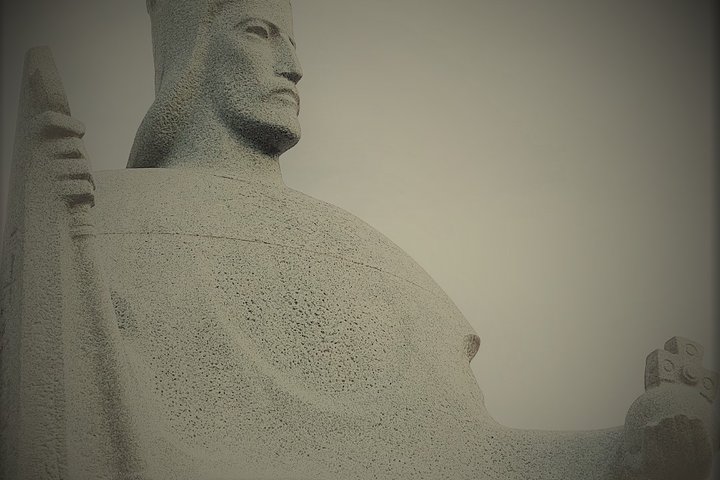 Karaliaus Mindaugo granito paminklas Vilniaus pilių teritorijoje. Mindaugas nufotografuotas iš profilio. Jis sėdi soste.