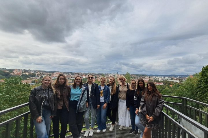 Nuotraukoje žmonių grupė pozuoja Altanos bokštelio terasoje. Už jų nugarų atsiveria viena gražiausių panoramų Vilniuje.