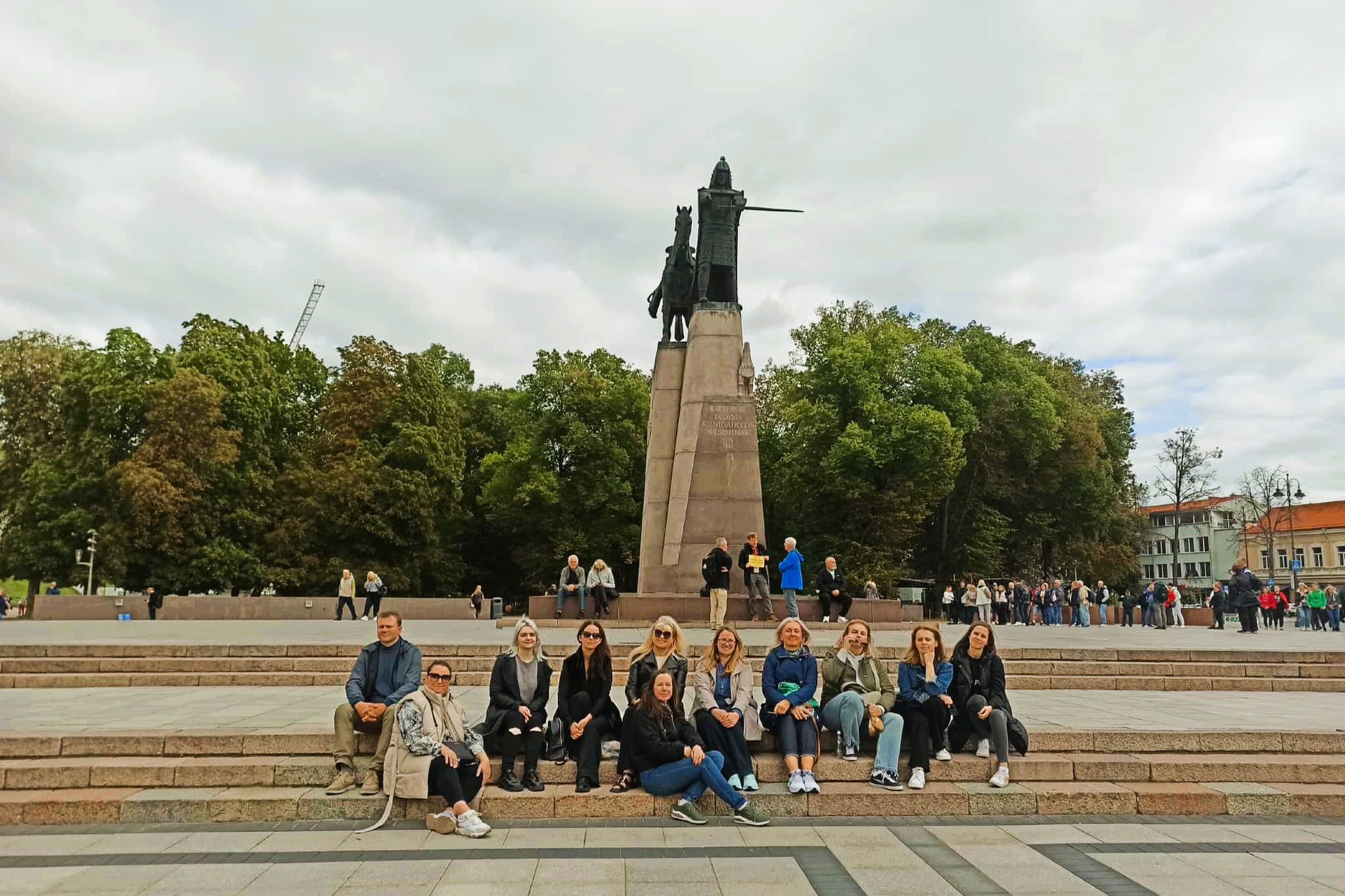 Nuotraukoje grupė žmonių pozuoja prie paminklo Gediminui.