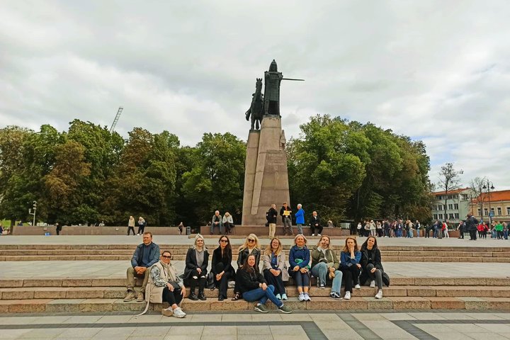 Nuotraukoje grupė žmonių pozuoja prie paminklo Gediminui.