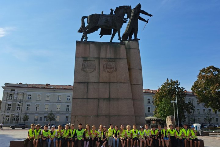 Nuotraukoje didelė vaikų grupė dalyvauja ekskursijoje „Gediminas ir Vilniaus trys pilys“.