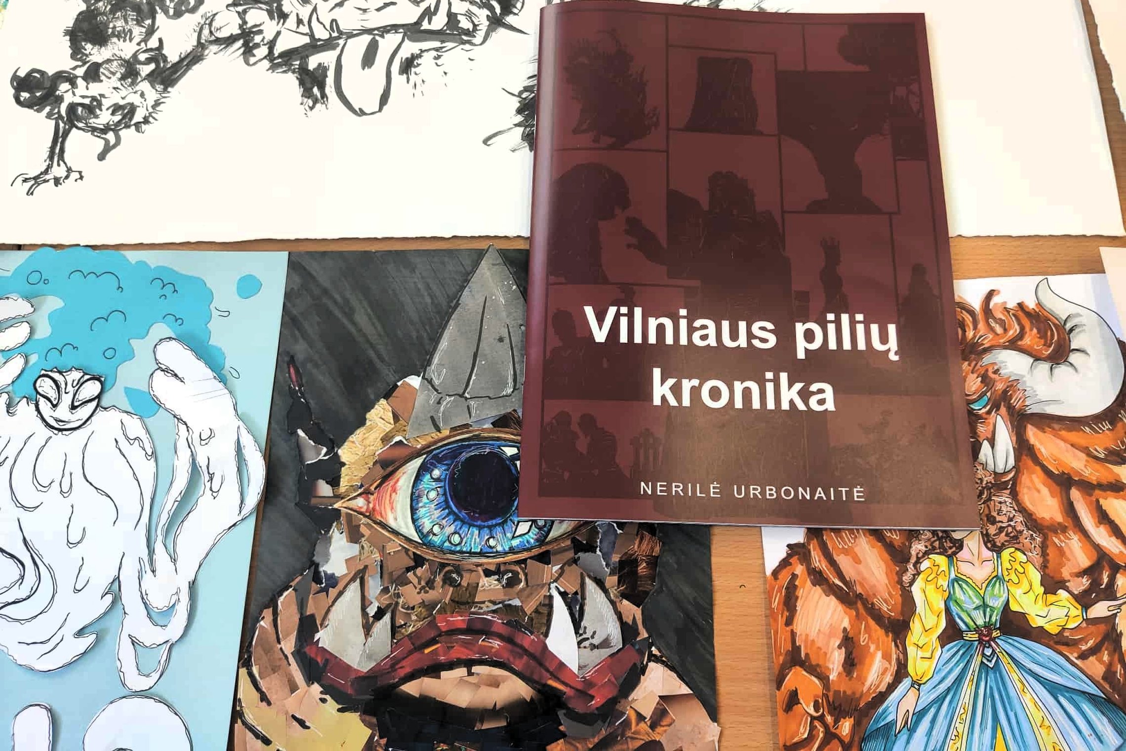 Knyga „Vilniaus pilių kronika“ padėta ant studentų piešinių ir iliustracijų.