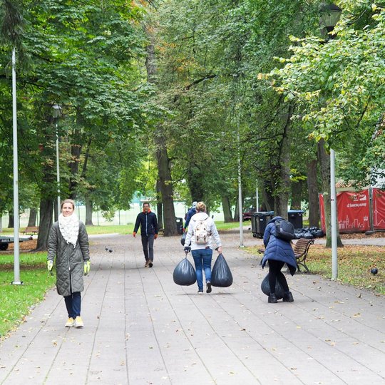 Savanoriai surinktus obuoliukus ir sugrėbtus lapus šiukšlių maišuose neša į surinkimo ir išvežimo vietą