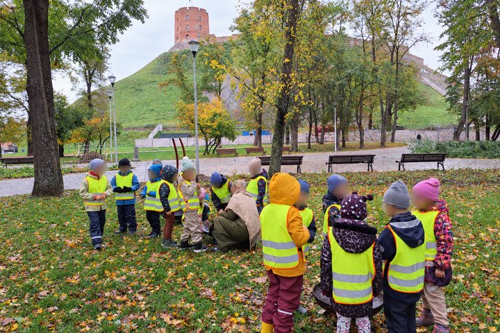 Vaikai su šviesą atspindinčiomis liemenėmis susibūrę Gedimino kalno papėdėje ugnies skeltuvu ir brauktuku bando įžiebti kibirkštį.