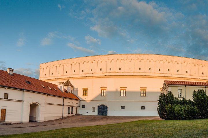 Vilniaus pilių teritorijoje esantis Senasis arsenalas – šviesių sienų, apvalios formos istorinis pastatas su mažais langais, vakaro saulės apšviestas vidiniame kieme.