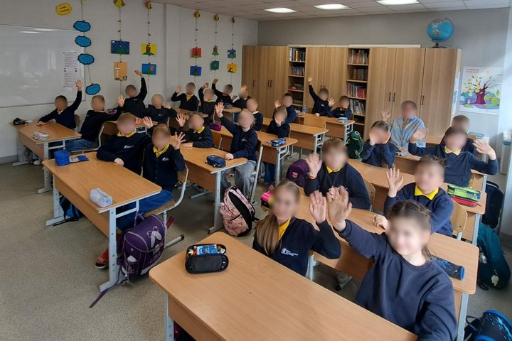 Nuotraukoje mokyklos klasė. Suoluose sėdi mokiniai. Jie dalyvauja edukacijoje.