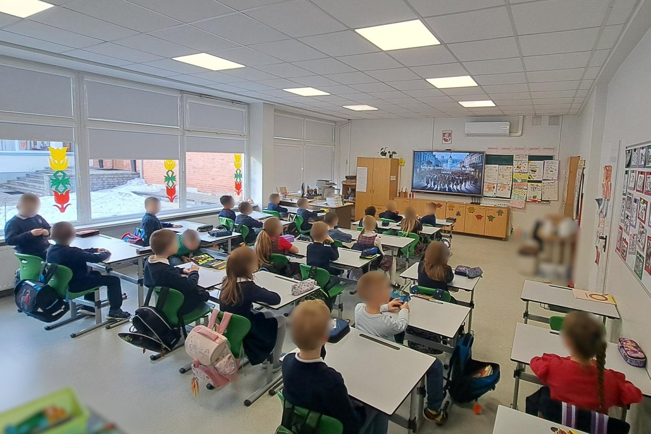 Nuotraukoje mokiniai dalyvauja edukacijoje „Nuo vienos laisvės iki kitos“. Jie sėdi suoluose klasėje. Klasė šviesi.