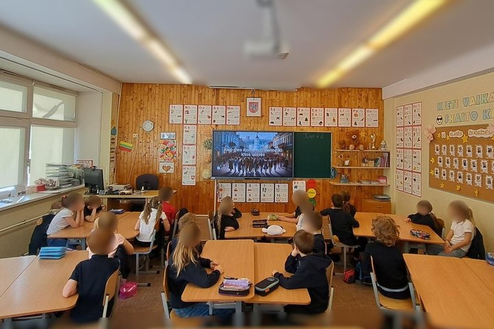 Nuotraukoje mokiniai klasėje. Jie žiūri į ekraną. Ekrane edukacijos tema „Nuo vienos laisvės iki kitos“