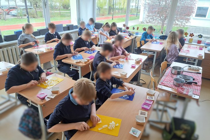 Mokiniai klasėje gamina muilą – prie stalų pjausto muilo pagrindą, dėlioja gabalėlius ir ruošia savo kūrinius edukacijos metu.