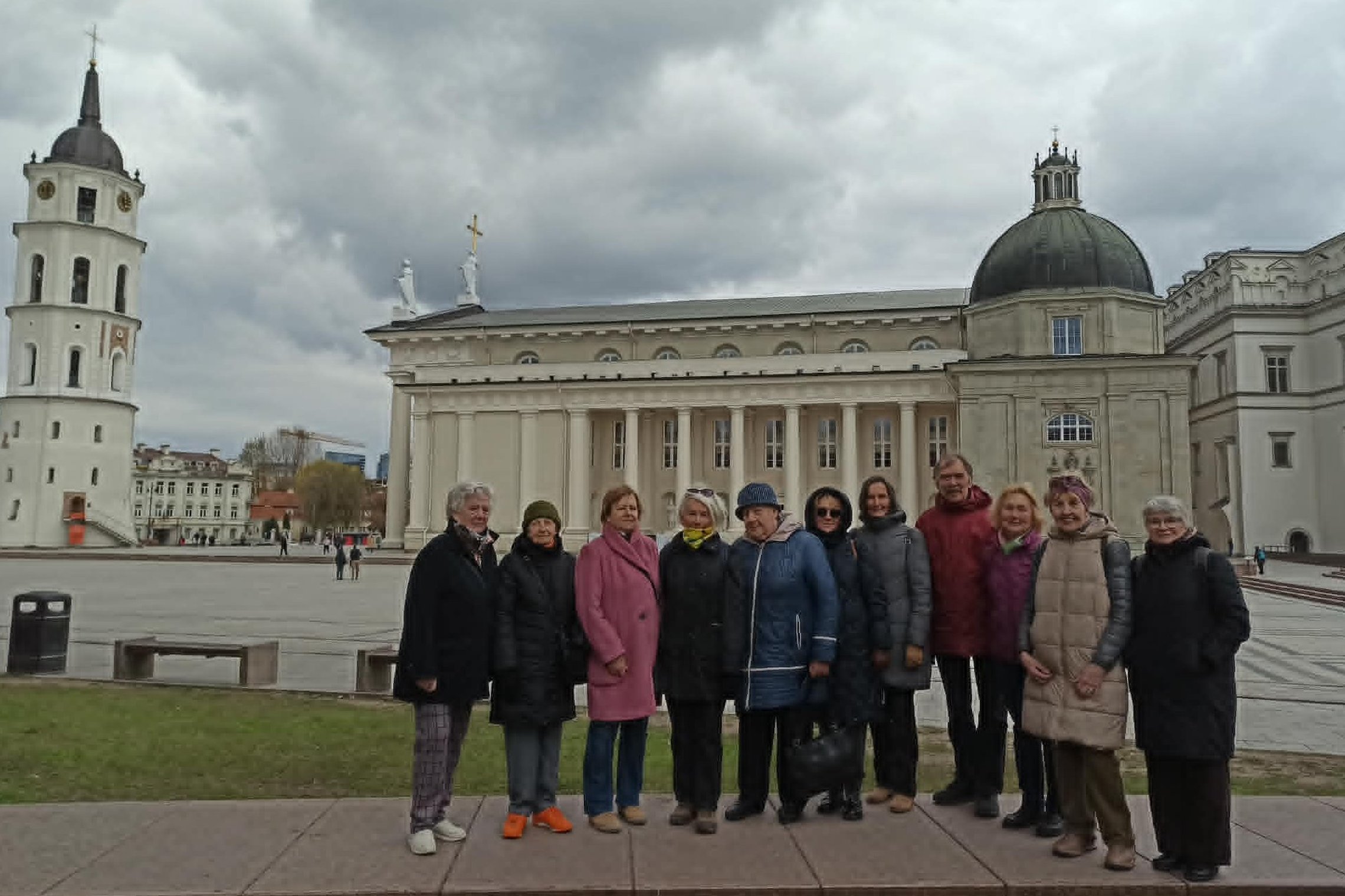 Trečiojo amžiaus universiteto studentai ekskursijos metu Vilniaus pilių teritorijoje klausosi gidės pasakojimų apie istorines meilės istorijas ir Vilniaus katedros architektūrą.