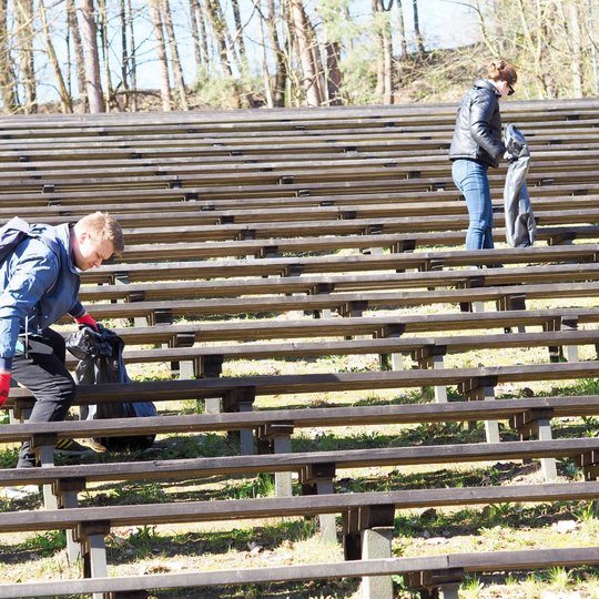 Thermo Fisher savanoriai renka šiukšles tarp koncertinės estrados suolų.