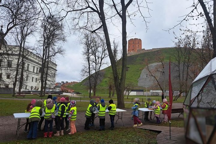 Nuotraukoje mokiniai Gedimino pilies kalno papėdėje stato savo piliakalnių modelius iš smėlio. Jie dalyvauja edukacijoje Vilniaus pilyse.