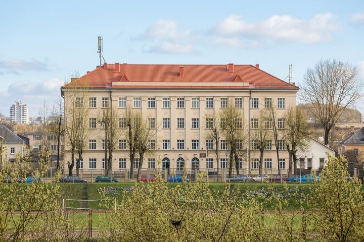 Vilniaus Šolomo Aleichemo gimnazijos pastatas – šviesi, trijų aukštų mokykla su raudonu stogu, matoma iš priekio, priešais ją – žalioji zona su medžiais ir sporto aikštynu.