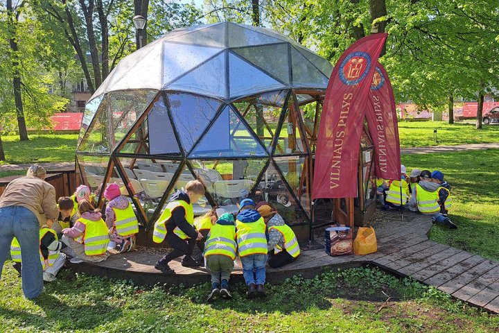 Vilniaus lopšelio-darželio „Lakštingala“ vaikai edukacijos „Piliakalniai ir Vilniaus pilys – ant kalnų gimusi galia“ metu prie Vilniaus pilių edukacinio kupolo žalioje parko aplinkoje.