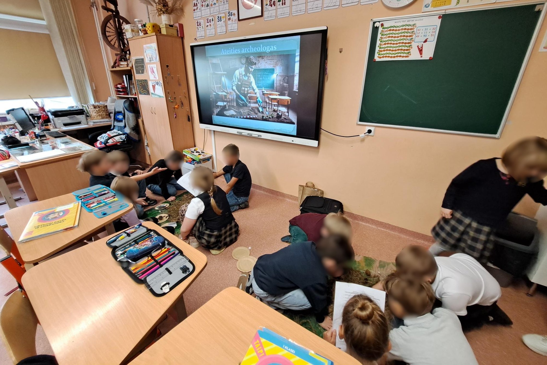 Pirmokai klasėje dalyvauja archeologinėje edukacijoje – dirbdami grupėse tyrinėja „žemės sluoksnį“, ieško radinių ir kuria pasakojimus apie žmonių gyvenimą.