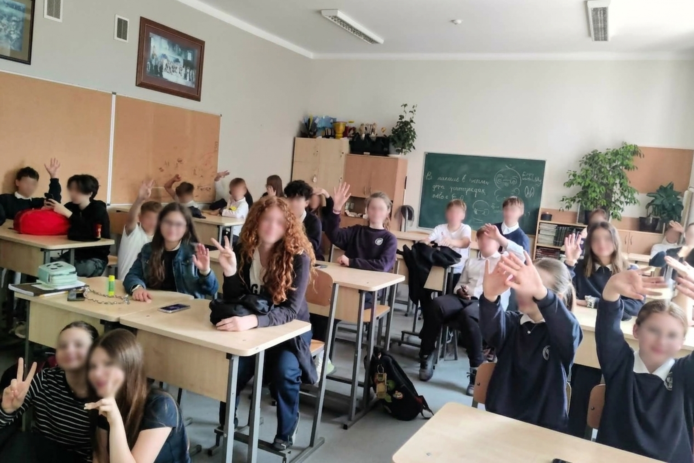 Klasėje sėdintys Vilniaus Šolomo Aleichemo ORT gimnazijos mokiniai šypsosi ir moja kamerai po gyvos istorijos pamokos. 