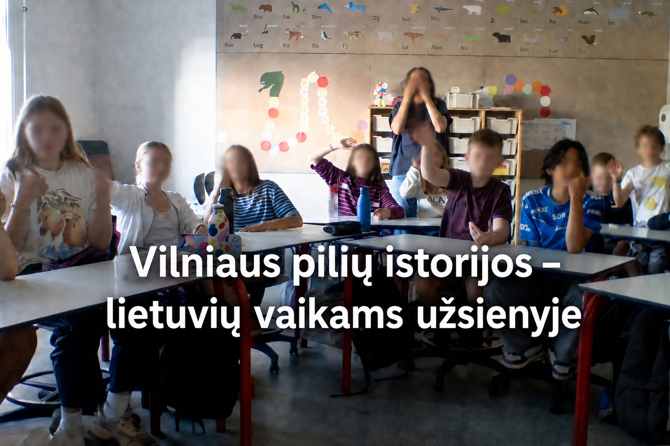Vaikai klasėje dalyvauja nuotolinėje edukacijoje apie Vilniaus pilių istoriją; nuotraukoje matomas užrašas „Vilniaus pilių istorijos – lietuvių vaikams užsienyje“.