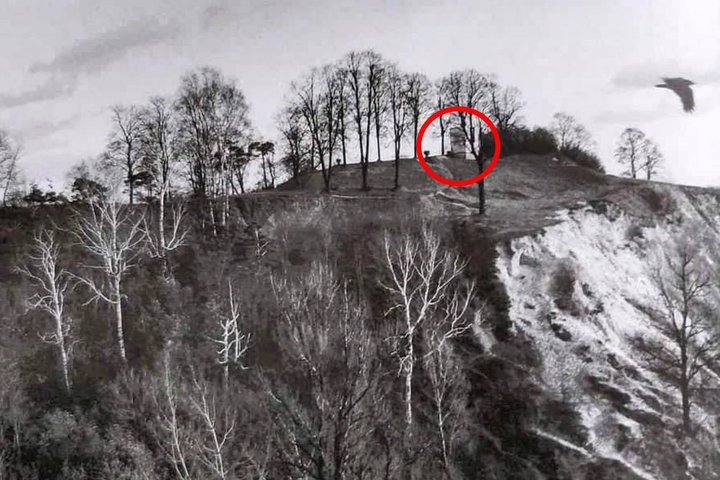 Nespalvotoje nuotraukoje matomas Altanos kalnas su medžiais, šlaitu ir viršuje raudonu apskritimu pažymėtu Altanos bokšteliu.