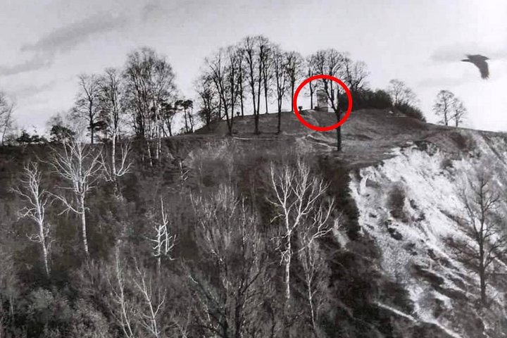 Altanos kalvos šlaitas ir ant kalvos stovintis bokštelis, pažymėtas raudonu apskritimu. Dešinėje danguje skrenda paukštis.