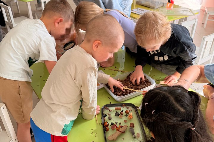 Mažieji Svajonių darželio ugdytiniai archeologijos edukacijos metu tyrinėja smėlio sluoksnius, ieško istorinių radinių ir susipažįsta su archeologų darbu, mokydamiesi „skaityti žemės knygas“.