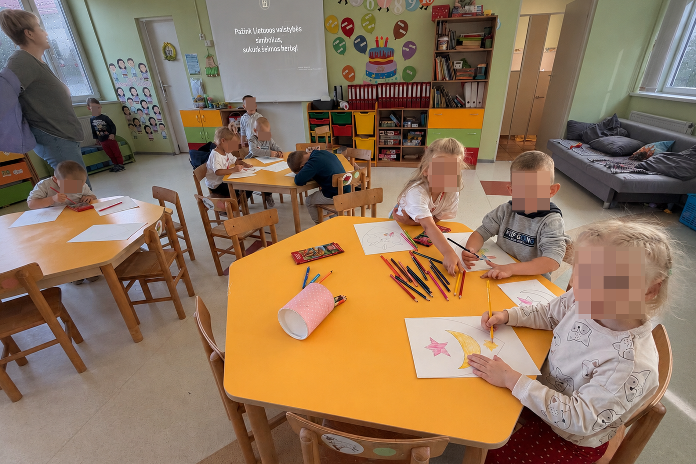 Turgelių Aistuvos mokyklos-darželio ugdytiniai edukacijos metu susėdę prie stalų kuria spalvingus šeimos herbus, susipažįsta su Lietuvos valstybės simboliais ir demonstruoja savo kūrybinius darbus.